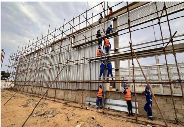 Construção industrial em Angola com equipa em obra e estruturas metálicas